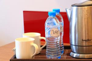 eine Flasche Wasser und zwei Tassen auf dem Tisch in der Unterkunft The Ray Hotel and Studios in Beirut
