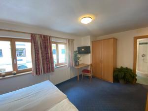 - une chambre avec un lit, un bureau et des fenêtres dans l'établissement Apartment 54, à Sankt Anton am Arlberg