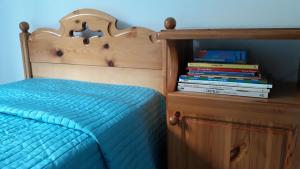 a bed with a wooden headboard and a stack of books at Casa vacanza Terry a Sella Nevea in Sella Nevea