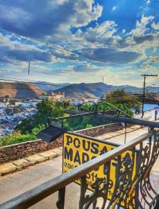 a yellow sign on a railing with a view of a city at Pousada Marotta in Ouro Preto