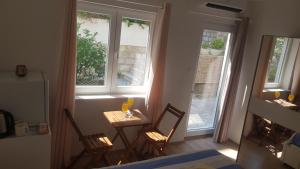 una mesa pequeña y sillas en una habitación con ventanas en Zorić Apartments & Rooms en Dubrovnik