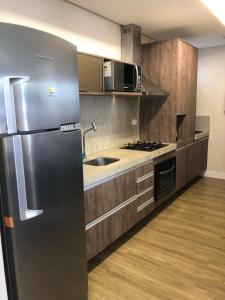 a large kitchen with a stainless steel refrigerator at Maceió Pajuçara Ed. Neo 1 in Maceió