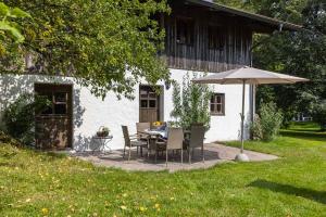 a table and chairs with an umbrella in front of a house at Ferienhaus Nöstlbach in Pittenhart