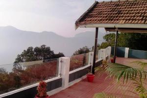 a house with a white fence and a view of the mountains at Le Rêve Holiday Home in Coonoor
