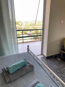sypialnia z łóżkiem i balkonem z widokiem na okolicę w obiekcie blue cielo sunny apartment w mieście Palaia Fokaia
