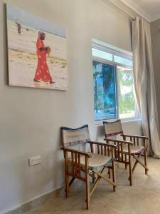 a dining room with chairs and a painting on the wall at Paje Beach Apartments & Hotel in Paje