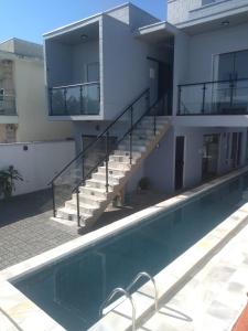 una casa con piscina frente a un edificio en Balli Suítes, en Ilha Comprida