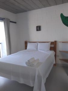 a white bed with two white towels on it at Balli Suítes in Ilha Comprida