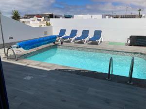 a swimming pool with blue chairs at Villa Maria in Playa Blanca