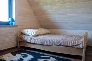 een klein bed in een houten kamer met een raam bij Domek na górce in Sztabin