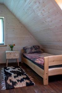 een slaapkamer met een bed in een blokhut bij Domek na górce in Sztabin