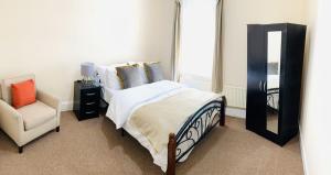 een slaapkamer met een bed, een spiegel en een stoel bij Beautiful 5 Bedroom Home to Enjoy in Ilford