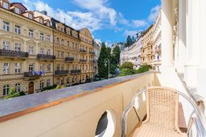 einen Stuhl auf einem Balkon mit Gebäuden in der Unterkunft Spa Hotel Anglický Dvůr in Karlsbad