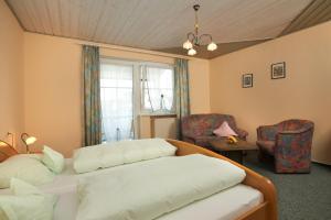 a bedroom with a bed and chairs and a window at Pension Martinus in Neustadt an der Donau