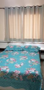 a bed with a blue comforter with flowers on it at Apto 2 quartos no centro de Bombinhas, 130 metros praia in Bombinhas