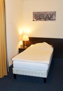 a bedroom with a bed and a lamp on a table at Hotel Schuurman in Emlichheim