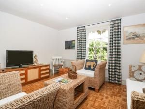 een woonkamer met rieten stoelen en een televisie bij Downton Lodge in Lymington
