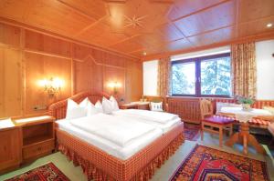 um quarto com uma cama grande, uma mesa e cadeiras em Hotel Pension Alpenrose em Lech am Arlberg