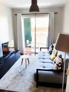 a living room with a blue couch and a tv at Santa Luzia's Pearl II - One Bedroom Apartment in Funchal