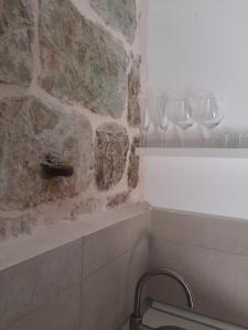uma casa de banho com dois copos de vinho numa parede de pedra em Violet em Vis