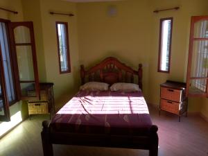 a bedroom with a bed with a wooden frame and windows at Cabaña Casablanca in La Granja