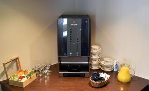 eine Kaffeemaschine auf einem Holztisch mit Weingläsern in der Unterkunft Hotel Schuurman in Emlichheim