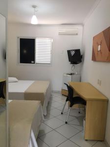 a room with a bed, chair, desk and a television at Hotel Sansaed in Cuiabá