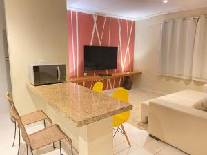 Sala de estar con cocina con barra y TV en Casa Kiwi - Aluguel Temporada, en Porto Seguro