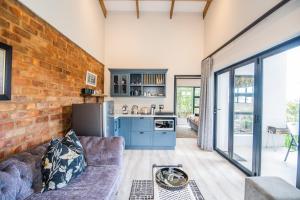uma sala de estar com um sofá e uma parede de tijolos em The Paper Fig House em Plettenberg Bay