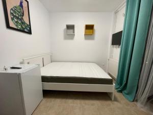 a small bedroom with a bed and a green curtain at Neo Saturn Residence in Saturn