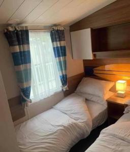 two beds in a small room with a window at 8 Berth,Waterside Leisure,Ingoldmells in Ingoldmells
