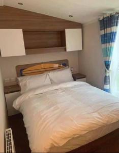 sypialnia z białym łóżkiem z drewnianym zagłówkiem w obiekcie 8 Berth,Waterside Leisure,Ingoldmells w mieście Ingoldmells