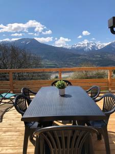 a table and chairs on a deck with mountains at chalet avec vue lac in Embrun