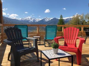 three chairs and a table on a deck with mountains at chalet avec vue lac in Embrun