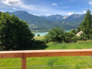 a view of a lake and mountains from a wooden fence at chalet avec vue lac in Embrun
