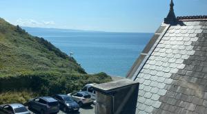 a group of cars parked on a hill next to the ocean at The Lobster Shack in Criccieth