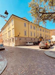 een groot geel gebouw met auto's geparkeerd op een parkeerplaats bij Palazzo Borgocolonne Apartments in Parma