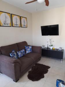 a living room with a brown couch and a flat screen tv at Residencial Palmas De Gurabo in Santiago de los Caballeros