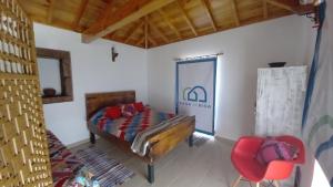 a bedroom with a bed and a red chair at Casa da Bisa - Santa Maria - Açores in Santa Bárbara