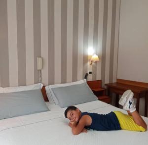 a woman laying on a bed in a hotel room at Hotel Marconi in Fiuggi