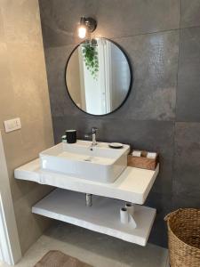 La salle de bains est pourvue d'un lavabo blanc et d'un miroir. dans l'établissement Villa Saracino, à Santo Spirito