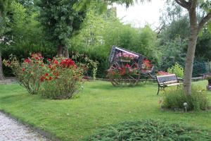 een bankje in een tuin met bloemen en een kar bij Hotel des Ducs in Alençon