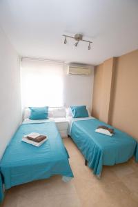 2 camas azules en una habitación con ventana en Casa Pitufo Calpe, bright duplex - see & mountain view, en Calpe