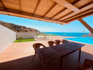 een houten terras met een tafel en stoelen en een zwembad bij Villas Calhau da Lapa 51 in Campanário