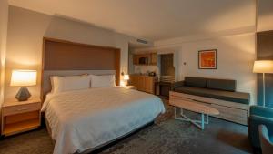 a hotel room with a bed and a couch at Holiday Inn & Suites - Merida La Isla by IHG in Mérida +51 photos