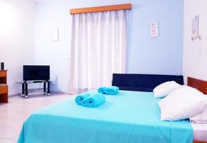 a blue bed with two blue towels on it at Pyrgos Hotel Apartments in Kremasti