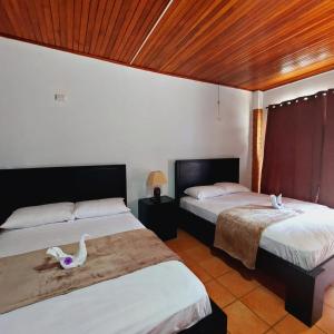 Dos camas en una habitación con dos cisnes. en Uruka Lodge en Alajuela