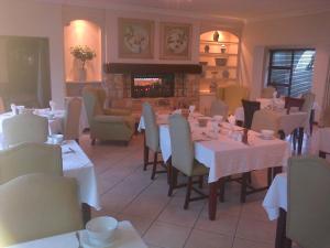 a dining room with tables and chairs and a fireplace at Pelagus Guest House in Hermanus