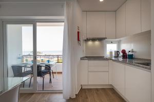 een keuken met witte kasten en een eetkamer met een tafel bij FishermenApartments - Carcavelos 32 in Carcavelos +17 foto's
