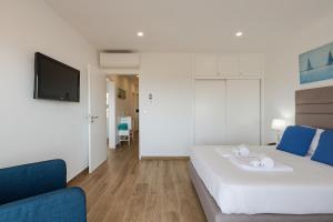 een slaapkamer met een wit bed en een blauwe bank bij FishermenApartments - Carcavelos 32 in Carcavelos